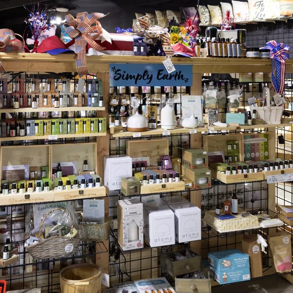 A retail display of "Simply Earth" essential oils, diffusers, and related products, with patriotic decorations.