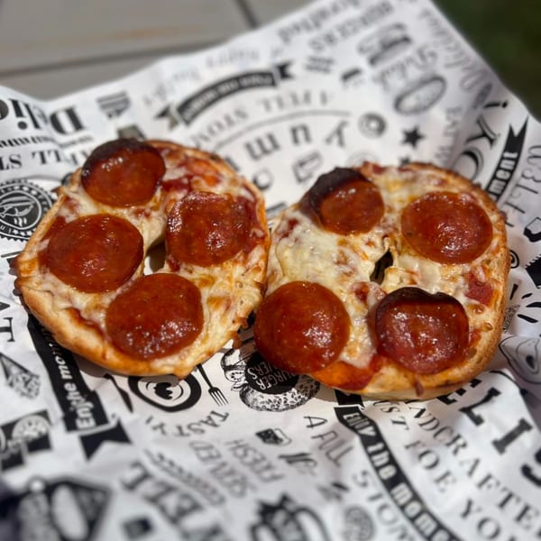 Two mini pepperoni pizzas on a branded paper liner, ready to be served at The Porch Breakfast & Brunch.